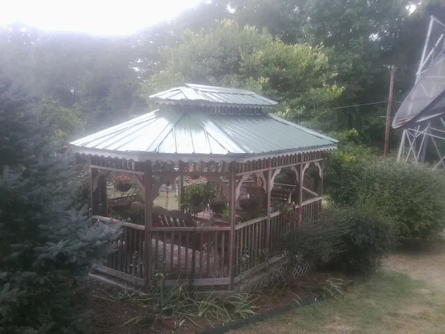 Green metal roof on a backyard gazebo surrounded by garden beds in Northwood